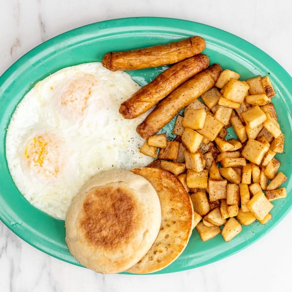 A University Diner breakfast plate with fried eggs, sausage links, home fries, and pancakes.
